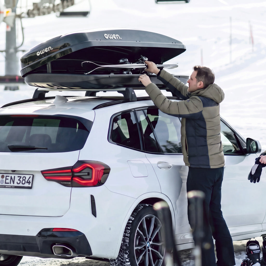OWEN® ROWA Dachbox 520L auf einem SUV beim Beladen mit Ski am Skilift