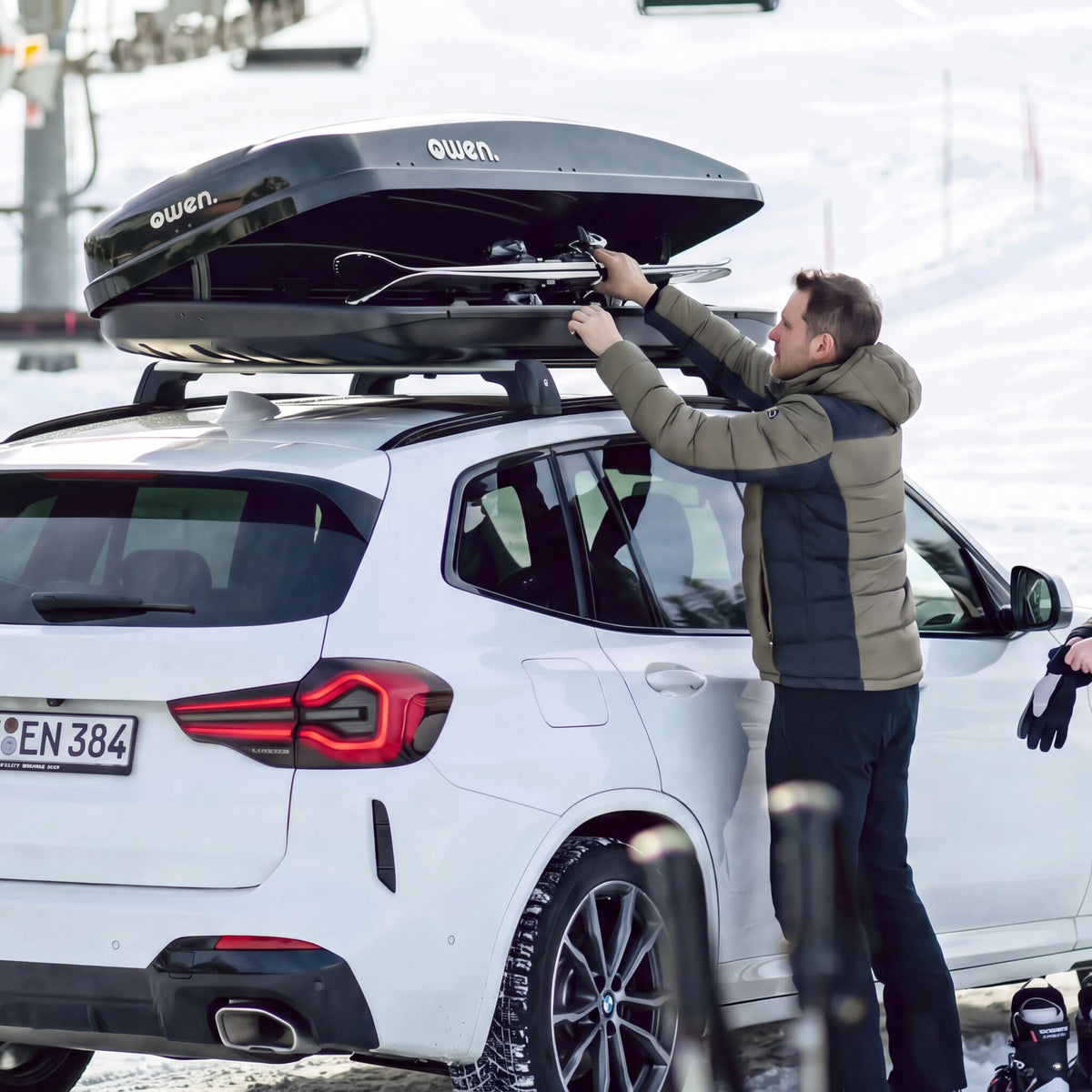 OWEN® ROWA Dachbox 520L auf einem SUV beim Beladen mit Ski am Skilift